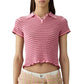 A woman wears the Smocked Shrunken Polo by Guest in Residence—a slim-fit, short-sleeved pink striped top with a ruffled hem—paired with high-waisted, smocked stripe pastel pants.