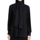 A person wears the Soomin Technical Crepe Top by Proenza Schouler, a long-sleeved black blouse with accordion pleats and a matching neck scarf, shown from the waist up.
