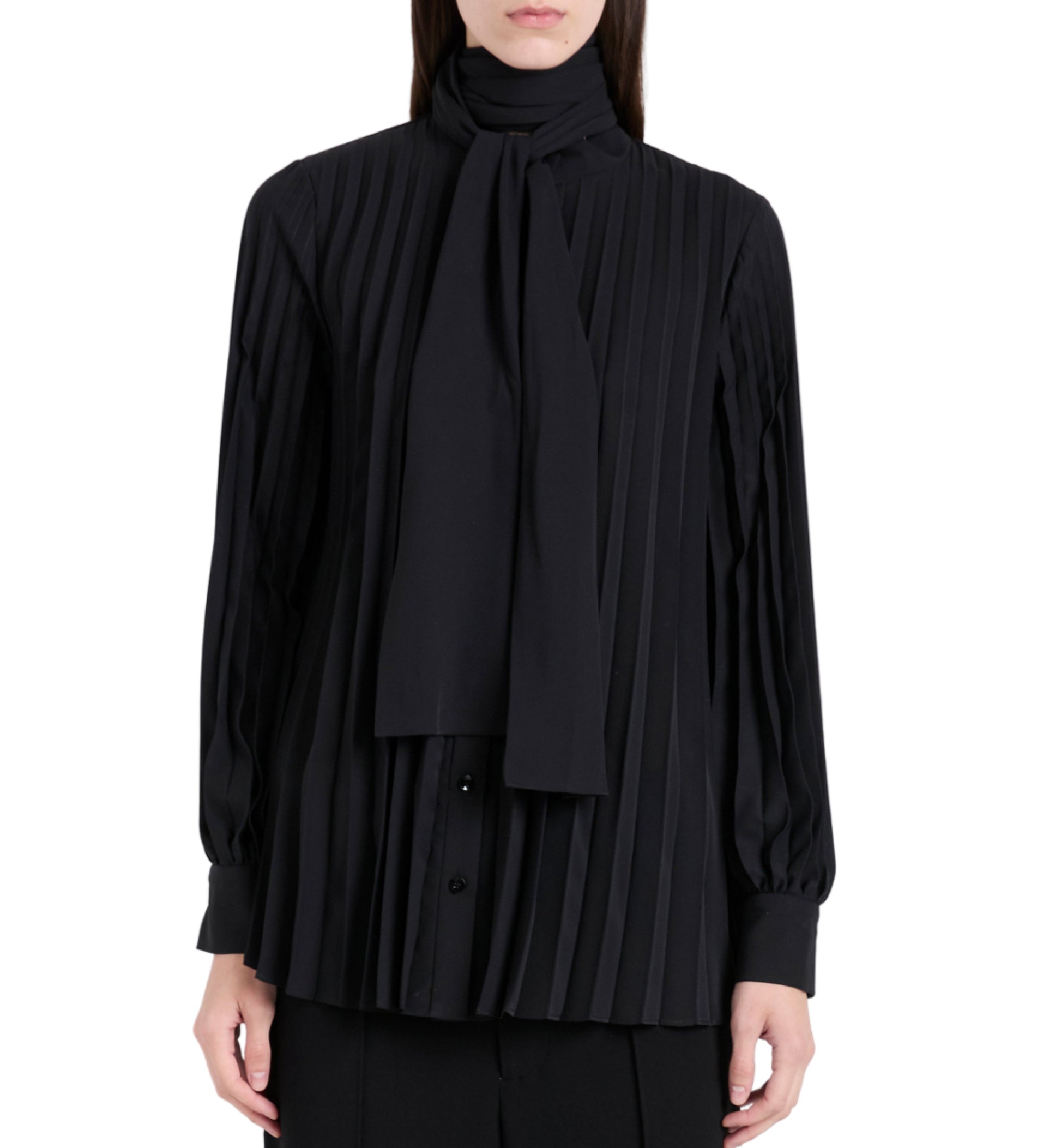 A person wears the Soomin Technical Crepe Top by Proenza Schouler, a long-sleeved black blouse with accordion pleats and a matching neck scarf, shown from the waist up.