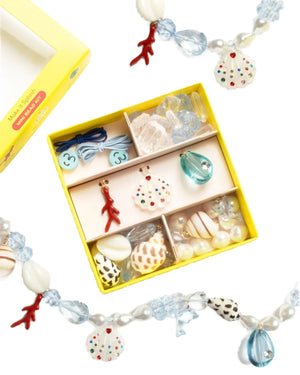 The Super Smalls Make It Splash Mini Bead Kit features a yellow box with six compartments holding assorted ocean-themed beads, pearls, waterproof beads, coral shapes, and seashell charms.