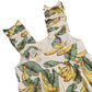 A close-up of Pink Chicken's Baby Girls' Via Bubble, a cotton cambric dress with ruffled straps, banana and green leaf print, and white front buttons.