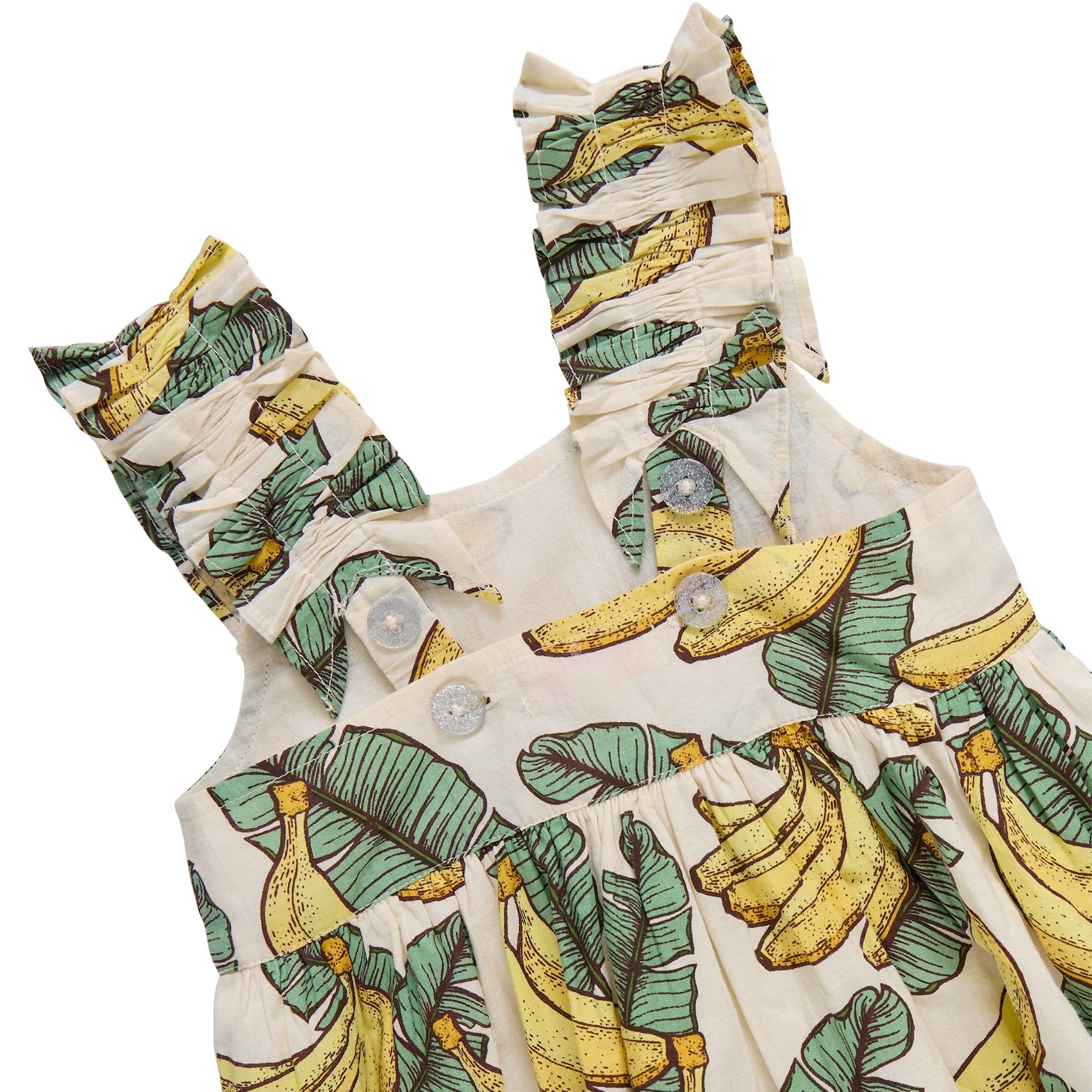 A close-up of Pink Chicken's Baby Girls' Via Bubble, a cotton cambric dress with ruffled straps, banana and green leaf print, and white front buttons.