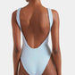 A person faces away from the camera, wearing the Hunza G Square Neck Swim in light blue. Made from signature crinkle fabric, this one-size swimsuit features a square neckline, low scoop back, and high-cut legs for a flattering fit.