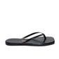 The Tkees Lily Square Toe Croc Sandal is a black flip-flop with thin straps, a textured sole, and a flat square toe—ideal for those seeking elegant footwear with modern style.