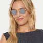A woman with long blonde hair models Krewe's St. Louis Mirrored Sunglasses and a sleeveless, textured dark top, highlighting their iconic classic style against a plain white background.