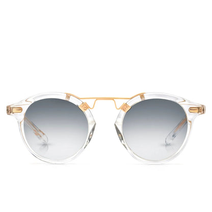 Krewe St. Louis Mirrored Sunglasses feature clear acetate round frames, a gold metal bridge, and a classic silhouette with grey gradient lenses, all displayed against a white background.