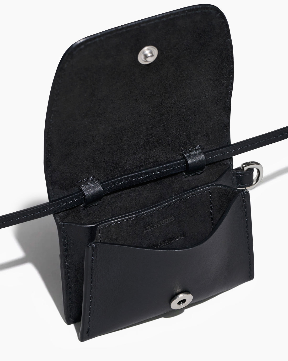 The Stella Wallet by Lie Studio is a black Italian cow leather crossbody with a flap lid, snap button closure, slim strap, and open view of the interior pocket—offering versatile style for any occasion.