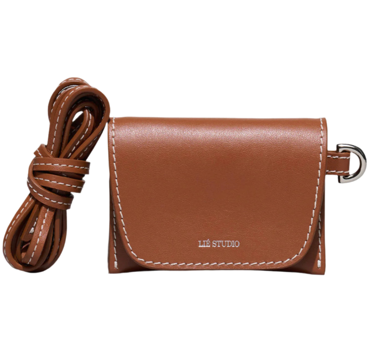 A compact brown Italian cow leather Stella Wallet by Lie Studio, with white stitching, a flap closure, and a detachable strap beside it. "LIE STUDIO" is printed on the front, giving it a stylish and versatile look.