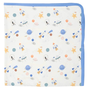 The Magnetic Me Stellar Tails Blanket by Magnetic Me is a white baby blanket with blue trim, adorned with repeated illustrations of rockets, planets, stars, and astronauts. It is made from eco-friendly TENCEL modal for a soft touch.