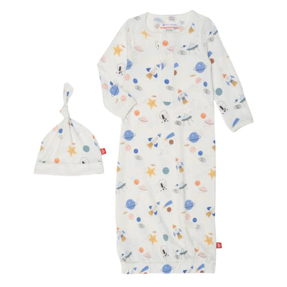 The Magnetic Me Stellar Tails Gown and Hat NB-3M is a white sleeper set designed from eco-friendly TENCEL™ modal, featuring a space-themed print with rockets, planets, and stars. It includes convenient magnetic closures for effortless dressing.