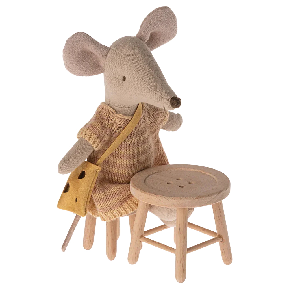 A fabric mouse doll in a knitted dress with a yellow bag sits on a wooden chair from the Mouse Hole Farmhouse collection next to the Maileg Table and Stool Set, Mouse.