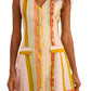 A woman in the Suni Dress by Hunter Bell NYC—a sleeveless, button-front mini dress in a linen-rayon blend with vertical multicolored stripes and two front pockets—holds a woven handbag.