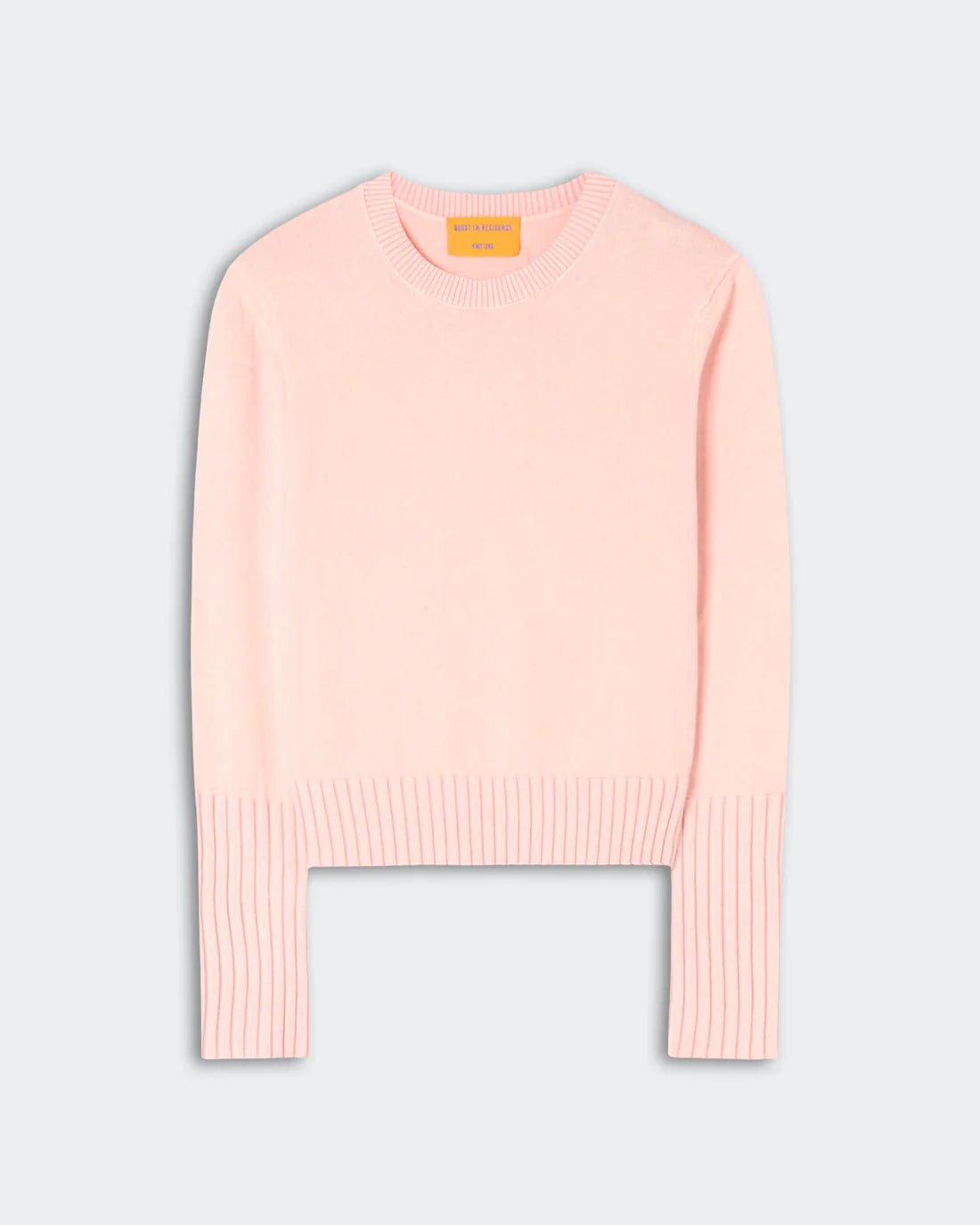 The Sunwash Shrunken Crew by Guest in Residence is a light pink cotton-cashmere crewneck sweater with ribbed cuffs, hem, and collar, shown flat against a plain light gray background—an ideal lightweight layer for effortless summer style.