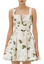 A person wearing the Agua Dress by Agua By Aguabendita, a sleeveless ivory A-line dress featuring a floral print and a feminine sweetheart neckline.