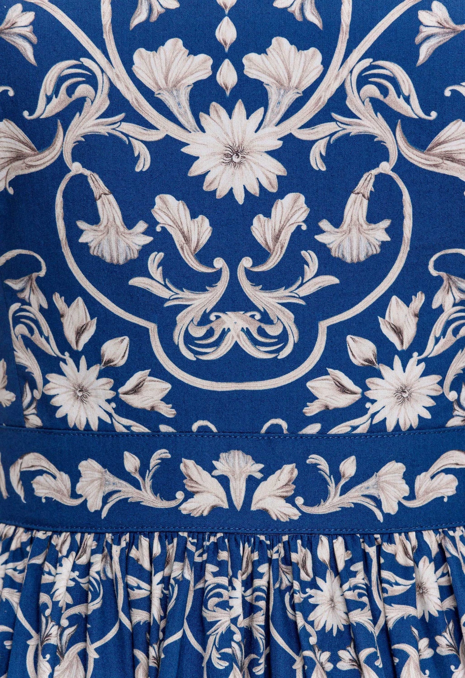 Close-up of blue fabric from the Lima Mini Dress by Agua By Aguabendita, featuring intricate white floral embroidery and pleated detailing at the hem.