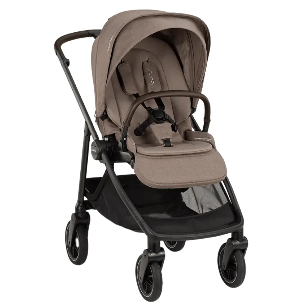 The Nuna SWIV Stroller by Nuna, in a beige finish with a black frame, offers a cushioned seat, safety harness, canopy, and an underneath storage basket. Highlighted by its stroller wheels capable of 360-degree swivel and button-activated rotation, this front-angle view seamlessly integrates comfort and convenience.