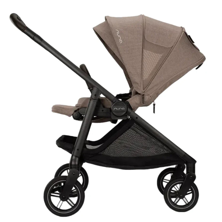 Side view of the beige Nuna SWIV Stroller with a black frame, showcasing its four 360-degree swivel wheels, sunshade canopy, and an under-seat storage basket.