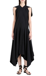 A woman models the Proenza Schouler Sybella Dress, a sleeveless black design with a handkerchief hem and flowing silhouette, paired with black lace-up sandals against a white background.