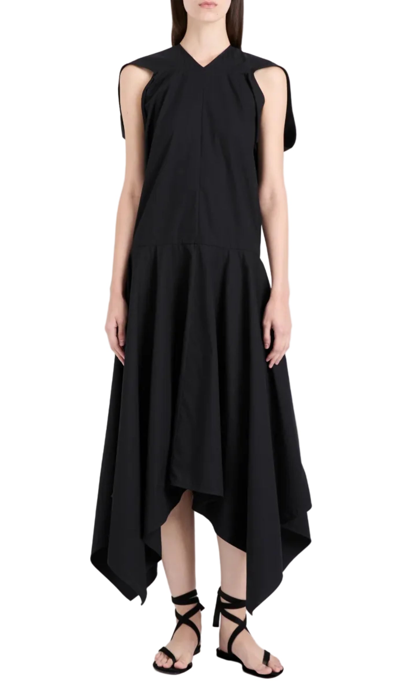 A woman models the Proenza Schouler Sybella Dress, a sleeveless black design with a handkerchief hem and flowing silhouette, paired with black lace-up sandals against a white background.
