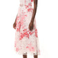 A woman wears the Monique Lhuillier Rose Printed Lace Midi Dress, belted at the waist for a feminine silhouette, paired with nude open-toe heels.