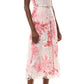 A woman wears the Monique Lhuillier Rose Printed Lace Midi Dress, styled with a thin belt and nude high-heeled sandals.