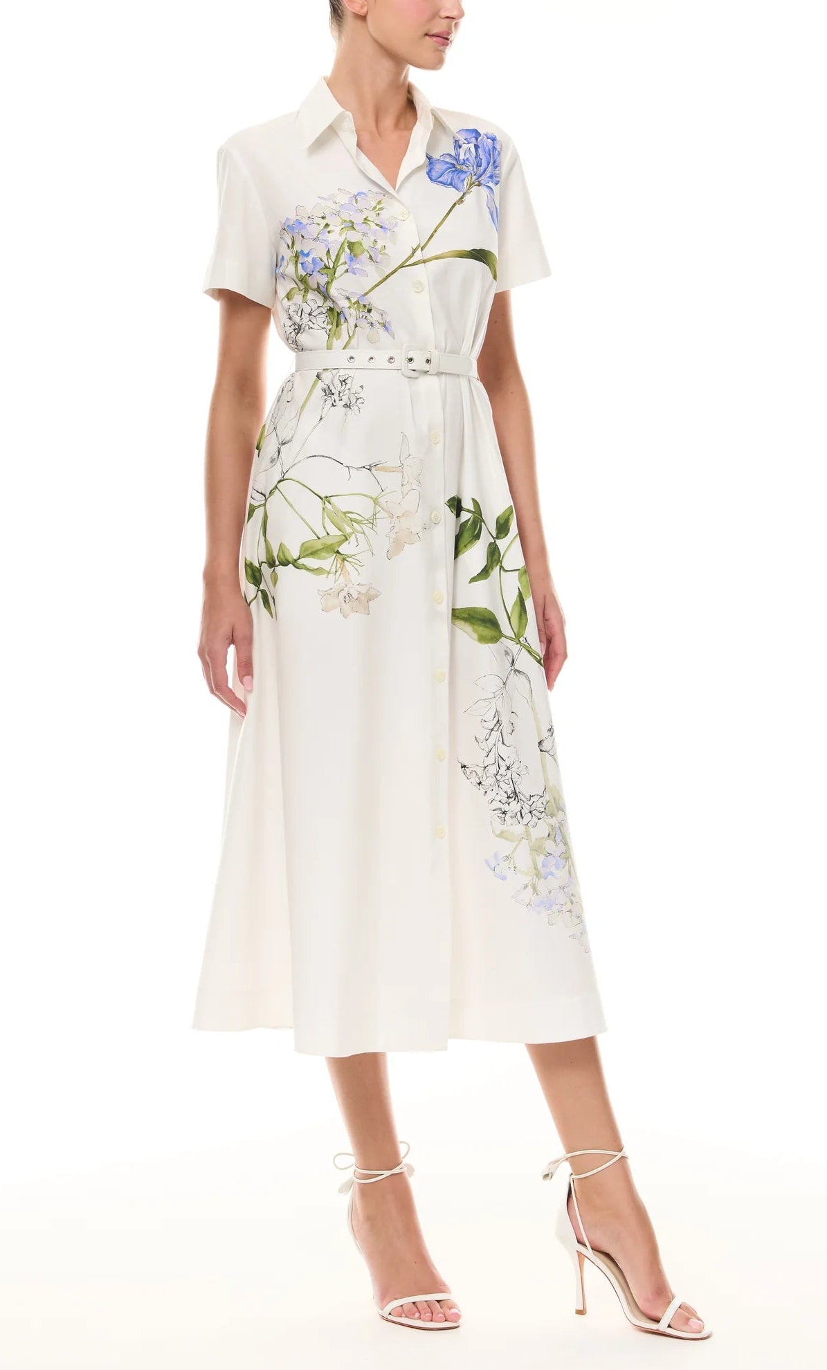 A woman wears the Monique Lhuillier Iris Printed Poplin Day Dress paired with white strappy high-heeled sandals.