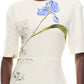 A person wearing the Monique Lhuillier Iris Bouquet Gown, an ivory multi short sleeve gown featuring a bold blue and green floral print reminiscent of an iris bouquet.