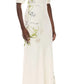 A woman wears the Monique Lhuillier Iris Bouquet Gown, a floor-length dress with short sleeves and a fitted waist, crafted from blue and green floral-printed crepe.