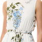 A person wearing the Monique Lhuillier Wisteria Floral Poplin Day Dress, featuring a blue floral print, sleeveless design, A-line skirt, and a thin white belt.