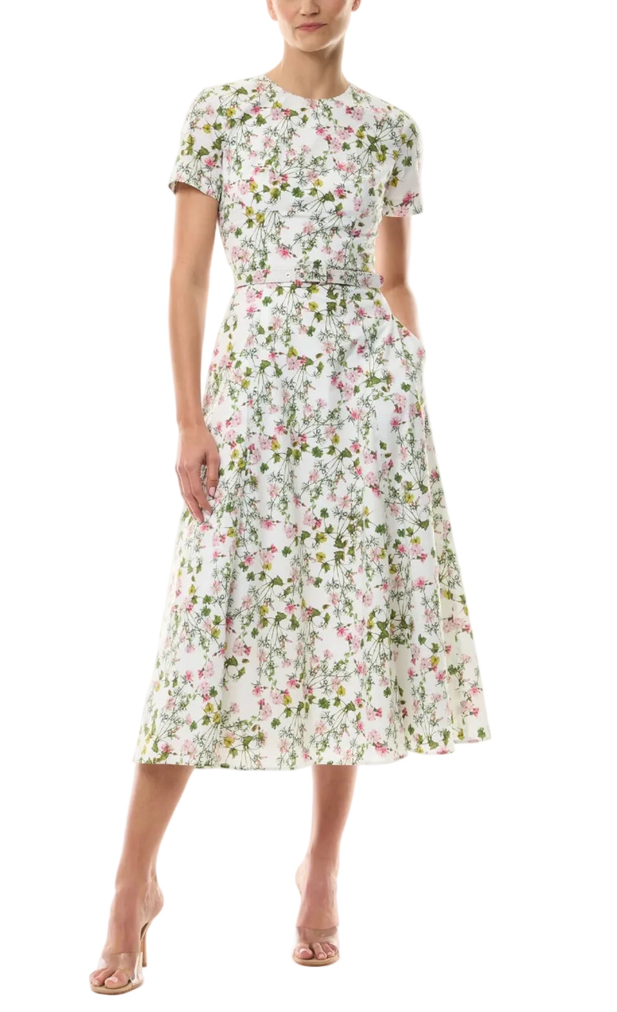 Woman in a Monique Lhuillier Ivy Bloom Short Sleeve Floral Day Dress with pink and green print, nude heels, standing against a white background.