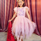 A young girl in a Girls’ Sparkle in Bloom Tutu Dress by Tutu du Monde, with a matching headband, stands on a star-shaped spot holding a red cone labeled “Tutu du Monde Productions” against a curtain backdrop.