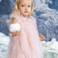 A young child in the Bébé Summit Sparkle Tulle Dress by Tutu du Monde stands with a snowball in a snowy, mountain winter setting.