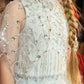 Child wearing a Diamond Drift Cafe dress by Tutu du Monde in Illusion Blue with beads, sequins, crystal latticework, and long braided hair draped over shoulders.