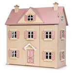 The Alouette House by Tender Leaf Toys is a wooden plywood dollhouse with a pink roof, chimneys, shutters, and a front door, featuring charming floral details on the window shutters against a plain background.