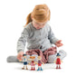 A young child sits cross-legged on the floor, arranging four Tender Leaf Toys Doll Family wooden dolls in front of them, set against a plain white background.