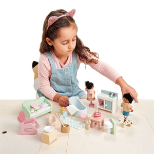 A young girl in a cat ear headband plays with the Countryside Furniture Set by Tender Leaf Toys, carefully arranging its miniature furniture and accessories on a light-colored table.