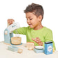 A young boy playing with a Tenderleaf Home Baking Set by Tender Leaf Toys in the kitchen.