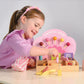 A young girl in a purple shirt plays with the Tender Leaf Toys Sweetie Pic'n' Mix Shop at a white table, using tongs and pretend pic n mix candies.