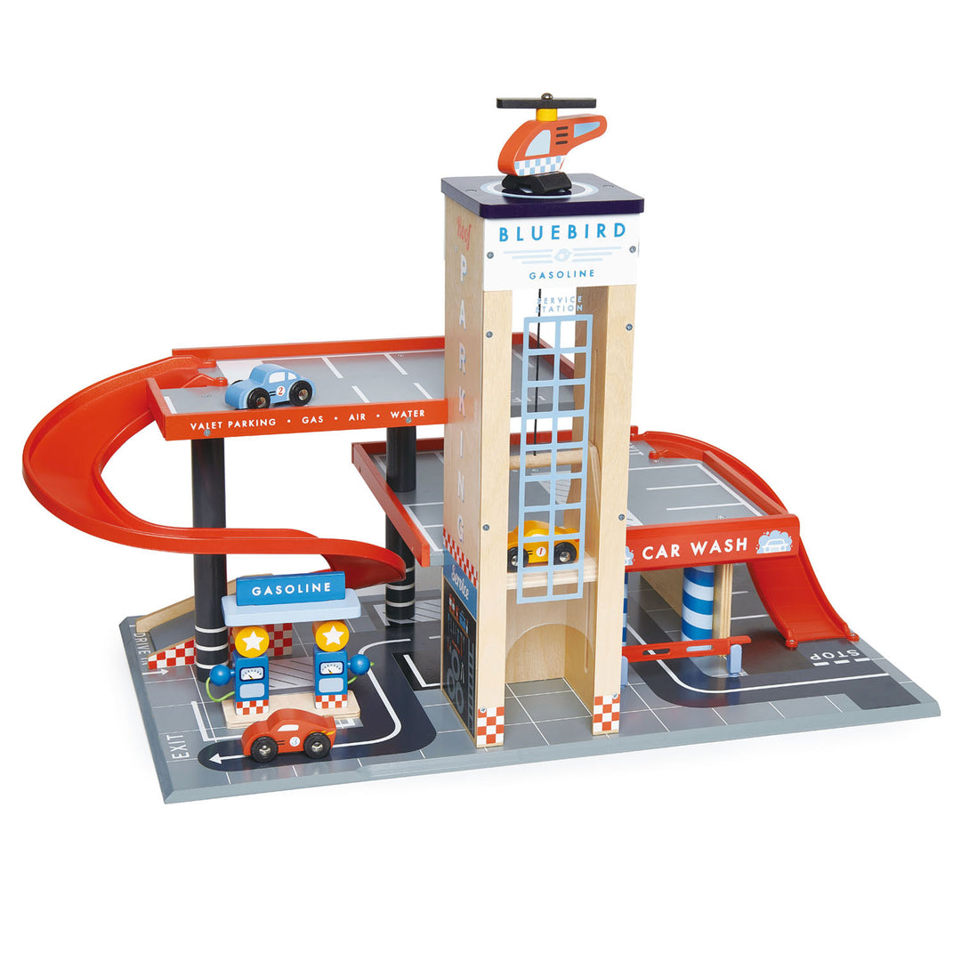 The Tenderleaf Blue Bird Service Station by Tender Leaf Toys includes a service station, car wash, and helipad. It features wooden cars and a helicopter that navigate the red spiral ramp. Complete with road markings for a realistic playground layout, this set offers endless fun.