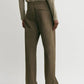 Model wears Toteme's Twisted Tailored Trousers in olive-green cotton, featuring a straight-leg cut and styled with a long-sleeve top, photographed from the back against a plain light background.