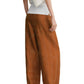 A person wearing Toteme Monogram Silk PJ Bottoms, a white top, and black sandals, photographed from the side.