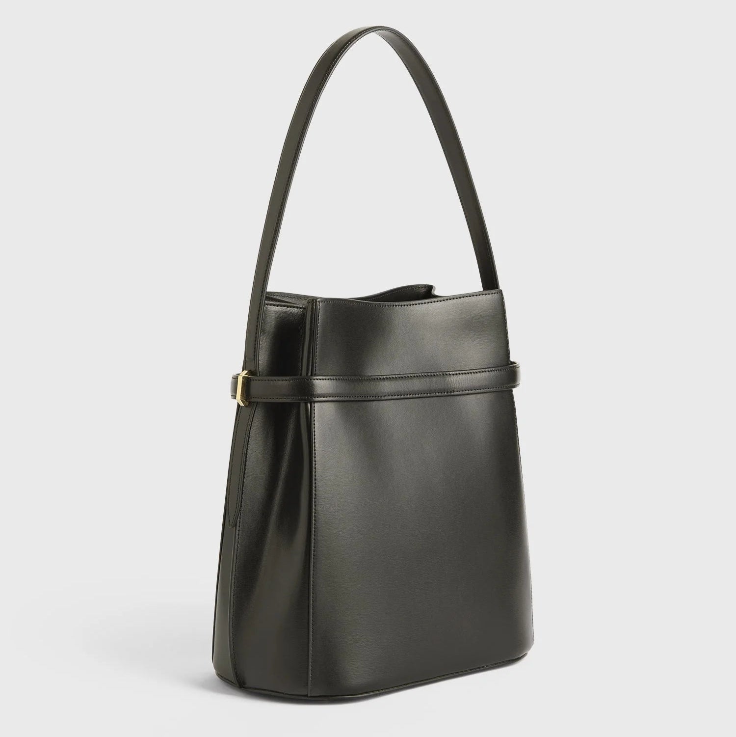 The Toteme Belted Bucket Bag, crafted from black Palmellato leather with a single shoulder strap and minimalistic design, stands upright against a plain white background.