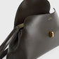 The Toteme T-Lock Clutch is a black Palmellato leather crossbody bag featuring a gold T-Lock clasp, shown partially open to reveal its interior.
