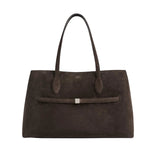 The Toteme Suede Lounge Tote is a spacious, dark brown Italian suede bag with dual handles and a slim horizontal strap with a metallic accent—ideal for everyday use.