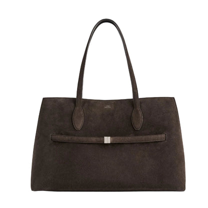 The Toteme Suede Lounge Tote is a spacious, dark brown Italian suede bag with dual handles and a slim horizontal strap with a metallic accent—ideal for everyday use.