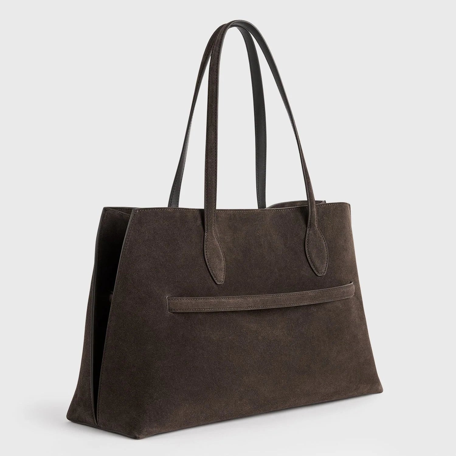 The Toteme Suede Lounge Tote is a dark brown Italian suede bag with two long handles and a front slip pocket, ideal for everyday use, shown against a plain light gray background.