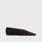 The Minimalist Suede Ballerinas by Toteme are black suede flats with a pointed toe and low heel, made in Spain and displayed in side profile against a plain white background.