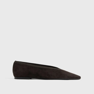 The Minimalist Suede Ballerinas by Toteme are black suede flats with a pointed toe and low heel, made in Spain and displayed in side profile against a plain white background.