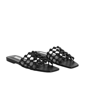 A pair of Toteme Braided Leather Bandeau Slides—black flat sandals with square toes and braided open woven straps—displayed on a white background.