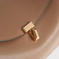 Close-up of the Toteme T-Lock Top Handle Bag in tan Palmellato leather, showcasing a gold rectangular T-Lock clasp on the front flap.
